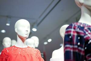 vrouw etalagepoppen zijn gekleed in gewoontjes kleren met een rood oranje thema in mode winkel Bij de afdeling op te slaan. foto