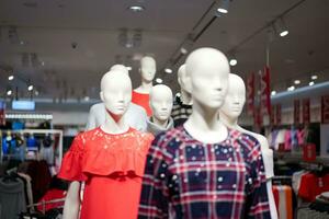 vrouw etalagepoppen zijn gekleed in gewoontjes kleren met een rood oranje thema in mode winkel Bij de afdeling op te slaan. foto