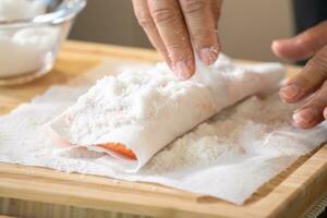 gemarineerd Zalm met zout Aan papier zakdoek voedsel rang Aan houten snijdend bord door professioneel hand- chef. foto