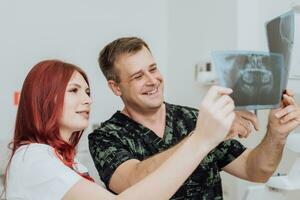 dokter tandarts met een assistent controleren de röntgenstraal orthopantomogram. tandheelkundig panoramisch radiografie foto