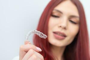 een vrouw met een mooi glimlach houdt aligners in haar hand- foto