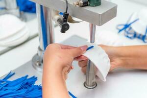 de meisje werken in een fabriek voor de productie van medisch maskers met nanovezel en soldeer loops met echografie Aan een machine. coronavirus en covid-19 bescherming.close-up. foto