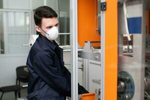 een arbeider staat Bij de machine in een fabriek voor de vervaardiging van medisch maskers met nanovezel. coronovirus en covid-19 bescherming foto