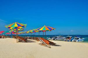 phuket, thailand, 2020 - stoelen en parasols op een strand met mensen en boten