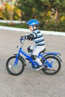 een kind in een helm en bescherming in een fiets rijden Aan natuur in de voorjaar foto