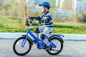 een kind in een helm en bescherming in een fiets rijden Aan natuur in de voorjaar foto