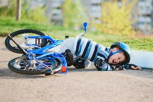 een klein kind viel van een fiets op de weg, huilen en schreeuwen in pijn. foto