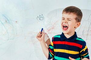 schreeuwen kind trekt Aan de muur met gekleurde potloden foto