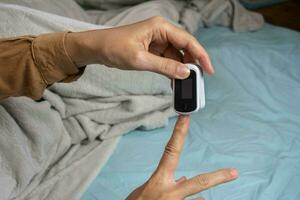 vrouwelijk handen met een pulse oximeter Bij de inhoudsopgave vinger. vrouw aan het liegen Bij de bed. gadgets voor Gezondheid zorg. concept van bepaling van zuurstof in de bloed. shotlistgezondheid foto
