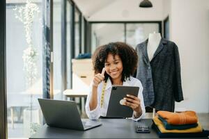 verschillend vrouw mode ontwerpers Bij werk met kleermaker centimeter Aan nekken en houdt tablet en smartphone. foto