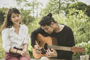 Aziatisch jonger Mens en vrouw spelen gitaar met geluk emotie foto
