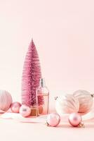 fles van vrouwen parfum of kunstmatig verstuiven Aan de achtergrond van een roze decoratief Kerstmis boom en ballonnen. verticaal visie. nieuw jaar nog steeds leven. foto