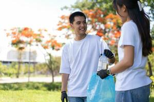 gelukkig jong Aziatisch studenten verschillend vrijwilligers met vuilnis Tassen schoonmaak Oppervlakte in de park, de concept van milieu behoud Aan wereld milieu dag, recyclen, liefdadigheid voor duurzaamheid. foto