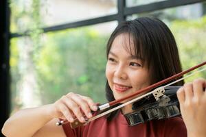 een aantrekkelijk vrouw aan het leren musicus Toneelstukken de viool Bij huis. componist creëren liedjes met draad instrumenten. dromerig violist vingers drukken strings Aan viool foto