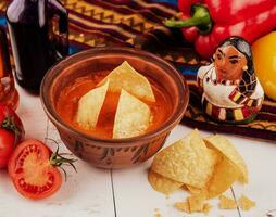 geel tortilla chips en salsa Aan wit tafel foto