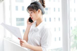 portret van een jonge zakenvrouw die bij het raam staat en telefoneert met haar partner