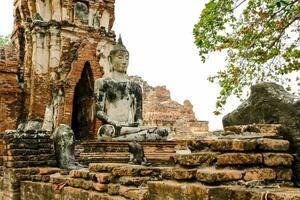 een Boeddha standbeeld is zittend in voorkant van een tempel foto