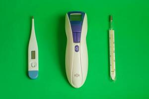 tekst het beste thermometer voor huis. drie verschillend types van thermometers Aan groen achtergrond. kwik, infrarood contactloos thermometer. kiezen thermometer voor huis foto