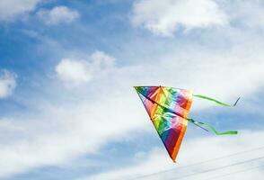 regenboog vlieger vliegend in blauw lucht met wolken in zomer met copyspace foto