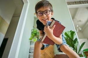 een jongen houdt een stack van boeken tegen de achtergrond huis bibliotheek. foto