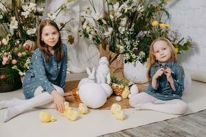 twee meisjes in een mooi Pasen foto zone met bloemen, eieren, kippen en Pasen konijntjes. gelukkig Pasen vakantie.