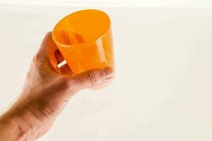 een hand- Holding een oranje plastic kop foto