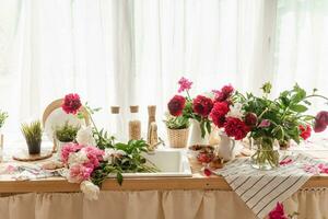 de keuken aanrecht is versierd met pioenrozen. de interieur is versierd met voorjaar bloemen. roze pioenen en zoet cupcakes Aan een houten aanrecht. interieur details. foto