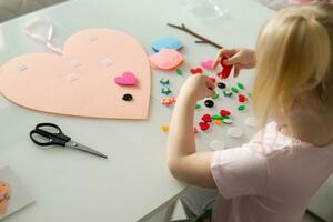 een blogger meisje maakt een voelde ambacht voor Valentijnsdag dag in de vorm van een hart. de concept van kinderen creativiteit en handgemaakt foto