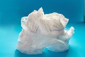 polyetteline transparant zak met gebruikt luiers Aan blauw achtergrond. onbewerkt afval. tekort van luiers gedurende coronavirus quarantaine. foto