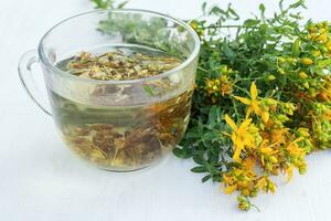transparant kop van st. John's wort remedie drank met bundel vers hypericum geel bloemen. pot van voorjaar honing. geneeskrachtig kruiden voor alternatief geneeskunde en homeopathisch remedies foto
