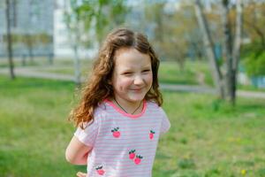 glimlachen meisje glimlacht Bij rimpel van neus. kind in achtergrond van school- in stad. wandelen gedurende coronavirus quarantaine. foto