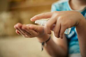 ontsmettingsmiddel in handen van kind. hand- behandeling is ontsmetting hulpmiddel. vernietigen virussen van oppervlakte van huid. veiligheid Bij risico van contracteren coronavirus. foto