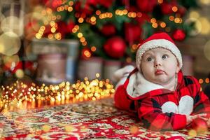 weinig zes maand oud baby gekleed net zo de kerstman claus. achtergrond voor Kerstmis kaart. de kind looks omhoog Bij de plaats voor inscriptie. foto