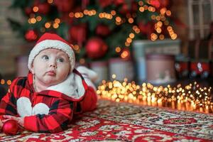 weinig zes maand oud baby gekleed net zo de kerstman claus. achtergrond voor Kerstmis kaart. de kind looks omhoog Bij de plaats voor inscriptie. foto