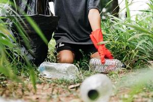 jongen man hand pick-up plastic fles in bos. milieu concept. foto