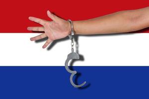 handboeien met hand op nederlandse vlag foto