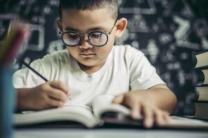 een jongen met een bril die in de klas schrijft foto