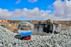 een glas bal zittend Aan top van een rots foto