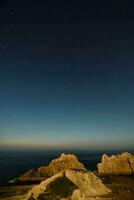 de nacht lucht over- de oceaan en rotsachtig kliffen foto