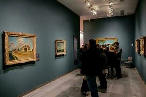 mensen op zoek Bij schilderijen in een kunst museum foto
