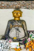 een groot gouden Boeddha standbeeld in voorkant van een muur foto