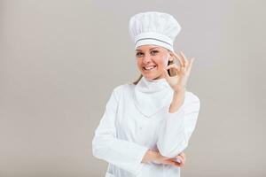 portret van mooi vrouw chef tonen OK teken Aan grijs achtergrond. foto