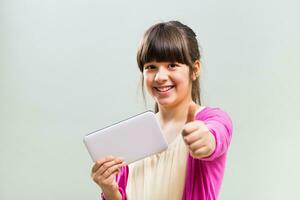 weinig meisje gebruik makend van digitaal tablet en tonen duim omhoog foto