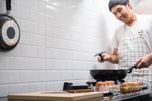 Aziatische chef-kok gebakken eieren op pan naar Thais eten in de keuken op gasfornuis de olie in pan kokende eieren en varkensvlees gekookt. voor het serveren aan het gelukkige gezin om samen thuis te eten foto