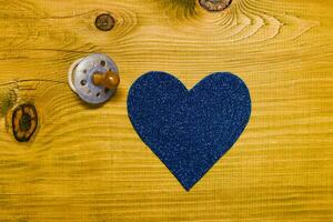 blauw hart met fopspeen Aan een houten deur foto