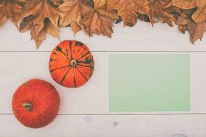 pompoenen en bladeren Aan een wit houten tafel met een blanco kaart foto