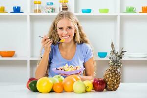 mooi meisje geniet aan het eten fruit salade Bij haar huis foto