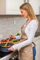 mooi vrouw Koken maaltijd in haar keuken foto