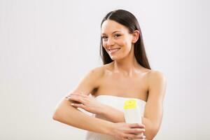 mooi vrouw toepassen vochtinbrengende crème Aan haar arm Aan grijs achtergrond foto