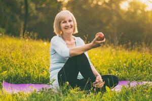 portret van actief senior vrouw aan het eten appel na oefening foto